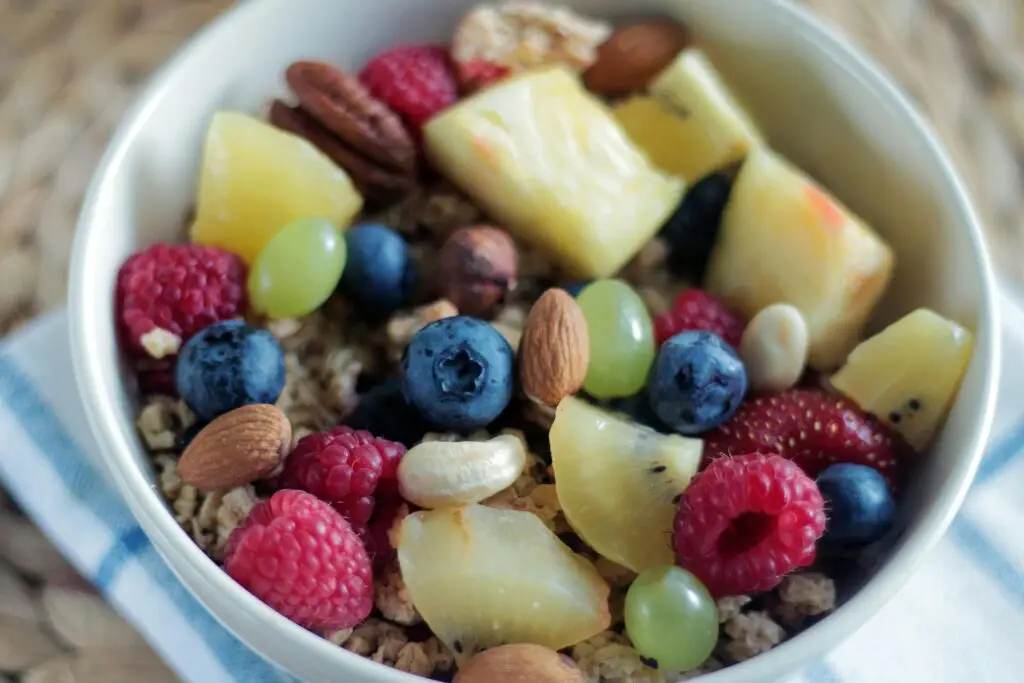 Close-up of a colorful muesli bowl with fresh berries, nuts, and pineapple.